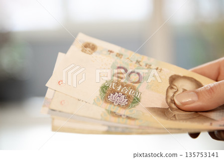 Woman holding a stack of twenty renminbi banknotes. Chinese yuan currency for finance, trade, economy, or travel concept. Woman holding a stack of twenty renminbi banknotes. Chinese yuan currency for finance, trade, economy, or travel concept. 135753141