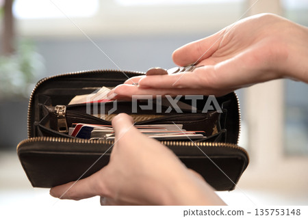 Woman holding coins and an open wallet, showing financial situation and everyday money management. Concept of saving or spending pocket change. Woman holding coins and an open wallet, showing financial situation and everyday money management. Concept of saving or spending pocket change. 135753148