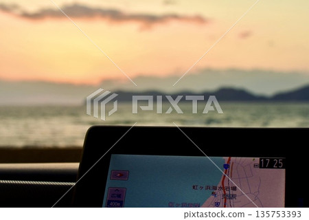 Car navigation system in the car and the sunset view from the car Car navigation system in the car and the sunset view from the car 135753393
