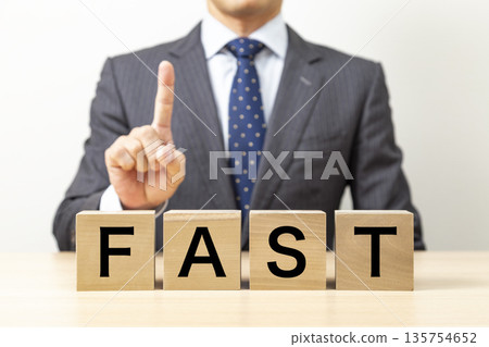 A block with the word "FAST" written on it and a businessman 135754652