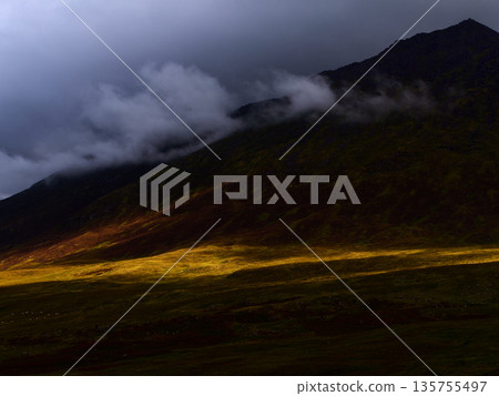 Golden sunlight illuminates a distinct path across the lower slopes of hill in Ireland. Golden sunlight illuminates a distinct path across the lower slopes of hill in Ireland. 135755497
