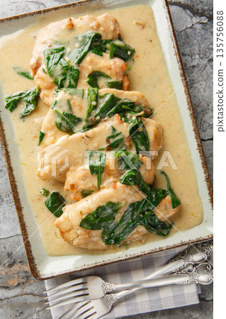 Creamy Chicken Florentine tender pan-fried chicken coated in an amazing garlic spinach white wine cream sauce close-up on a plate. Vertical top view Creamy Chicken Florentine tender pan-fried chicken coated in an amazing garlic spinach white wine cream sauce close-up on a plate. Vertical top view 135756088