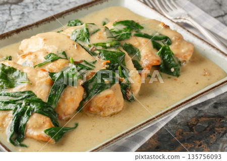 Close-up of Florentine chicken fried and then braised in a creamy wine sauce with spinach in a plate. Horizontal Close-up of Florentine chicken fried and then braised in a creamy wine sauce with spinach in a plate. Horizontal 135756093
