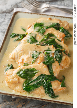 Chicken Florentine is a classic dish consisting of fried chicken fillet and spinach, served with a creamy sauce, close-up on a plate. Vertical 135756095