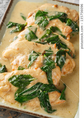 Creamy Chicken Florentine tender pan-fried chicken coated in an amazing garlic spinach white wine cream sauce close-up on a plate. Vertical Creamy Chicken Florentine tender pan-fried chicken coated in an amazing garlic spinach white wine cream sauce close-up on a plate. Vertical 135756096