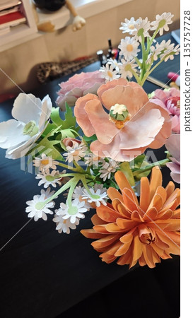 Artificial paper flowers arranged in a colorful handmade bouquet with soft indoor background and shallow depth of field. Image represents creativity, craft hobby, decoration and handmade art concept 135757728