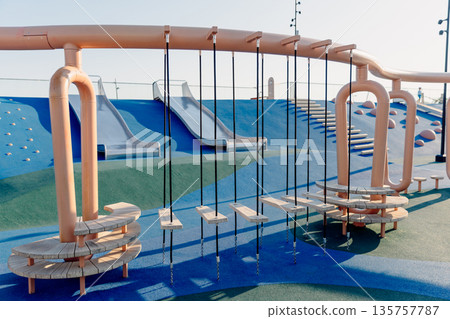 Modern playground with climbing elements and swings, showcasing safe urban design and outdoor recreation. Modern playground with climbing elements and swings, showcasing safe urban design and outdoor recreation. 135757787