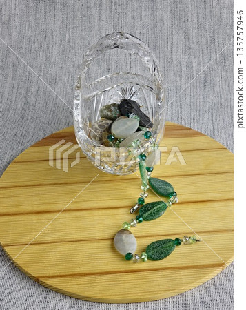 Handcrafted beads made of natural green and matte white agate with crackle effect on a wooden board background. Jewelry background. Handcrafted beads made of natural green and matte white agate with crackle effect on a wooden board background. Jewelry background. 135757946