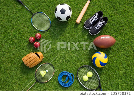 Collection of sport gear and balls forming a circular frame on green grass field with copy space Collection of sport gear and balls forming a circular frame on green grass field with copy space 135758371