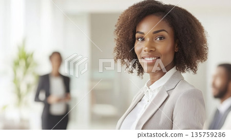Smiling African American businesswoman in an office setting, professional team interaction 135759286