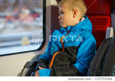 Young Boy Sitting by Train Window Looking Outside During Winter Journey Young Boy Sitting by Train Window Looking Outside During Winter Journey 135759368