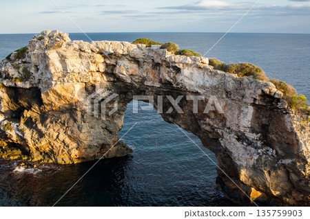 Es Pontas rock on Mallorca, Spain. Natural stone bridge between Cala Santanyi and Cala Llombards during the sunset close up 135759903