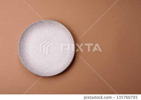 An empty round ceramic plate on a table, kitchenware. An empty plate An empty round ceramic plate on a table, kitchenware. An empty plate 135760785