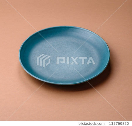 An empty round ceramic plate on a table, kitchenware. An empty plate An empty round ceramic plate on a table, kitchenware. An empty plate 135760820