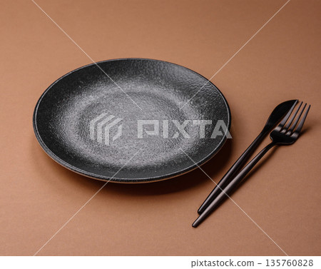 An empty round ceramic plate on a table, kitchenware. An empty plate An empty round ceramic plate on a table, kitchenware. An empty plate 135760828