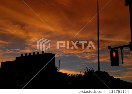 Red pedestrian signals and building silhouettes in a sunset city (urban twilight) Red pedestrian signals and building silhouettes in a sunset city (urban twilight) 135761134