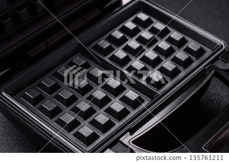 A waffle iron, an electric machine for making Belgian breakfast desserts. A waffle iron 135761211