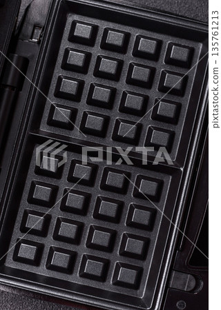 A waffle iron, an electric machine for making Belgian breakfast desserts. A waffle iron A waffle iron, an electric machine for making Belgian breakfast desserts. A waffle iron 135761213