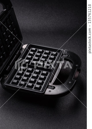 A waffle iron, an electric machine for making Belgian breakfast desserts. A waffle iron A waffle iron, an electric machine for making Belgian breakfast desserts. A waffle iron 135761218