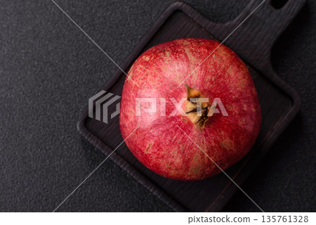 A juicy, ripe, whole red pomegranate as a source of beneficial nutrients. A whole red pomegranate 135761328