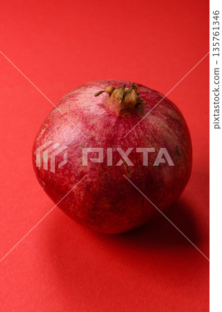 A juicy, ripe, whole red pomegranate as a source of beneficial nutrients. A whole red pomegranate 135761346