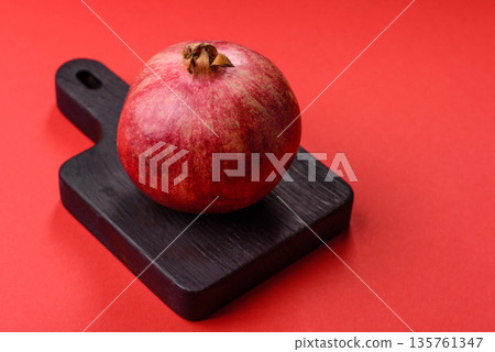 A juicy, ripe, whole red pomegranate as a source of beneficial nutrients. A whole red pomegranate 135761347