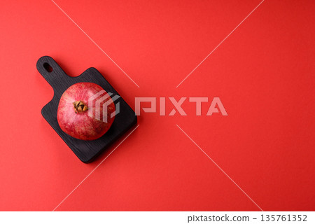 A juicy, ripe, whole red pomegranate as a source of beneficial nutrients. A whole red pomegranate 135761352