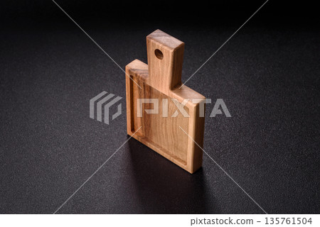 Wood, a wooden empty cutting board on a dark kitchen table. Wooden cutting board Wood, a wooden empty cutting board on a dark kitchen table. Wooden cutting board 135761504