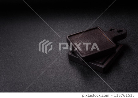 Wood, a wooden empty cutting board on a dark kitchen table. Wooden cutting board Wood, a wooden empty cutting board on a dark kitchen table. Wooden cutting board 135761533