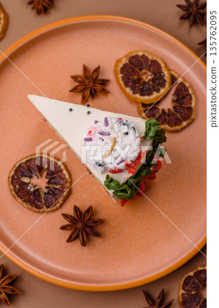 A slice of sweet layered cake with a Christmas ornament and fruit flavor. A slice of cake A slice of sweet layered cake with a Christmas ornament and fruit flavor. A slice of cake 135762095