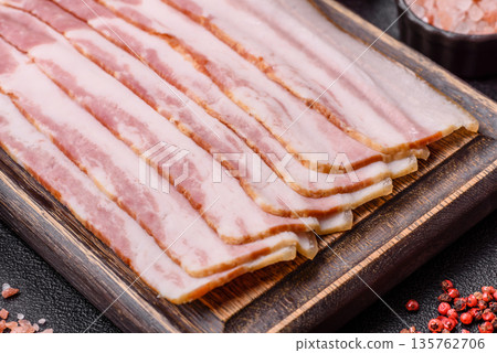 Raw smoked bacon slices, ham, jamon, or prosciutto strips for cooking. Raw bacon slices Raw smoked bacon slices, ham, jamon, or prosciutto strips for cooking. Raw bacon slices 135762706