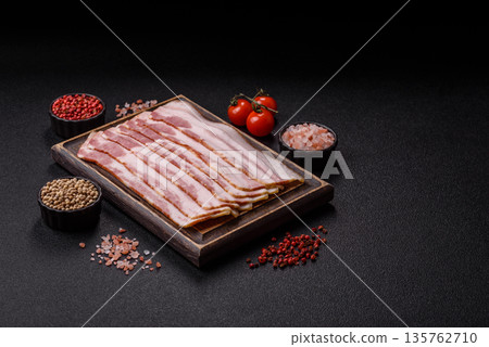Raw smoked bacon slices, ham, jamon, or prosciutto strips for cooking. Raw bacon slices Raw smoked bacon slices, ham, jamon, or prosciutto strips for cooking. Raw bacon slices 135762710