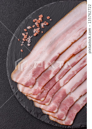 Raw smoked bacon slices, ham, jamon, or prosciutto strips for cooking. Raw bacon slices Raw smoked bacon slices, ham, jamon, or prosciutto strips for cooking. Raw bacon slices 135762722