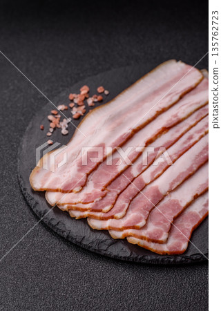 Raw smoked bacon slices, ham, jamon, or prosciutto strips for cooking. Raw bacon slices Raw smoked bacon slices, ham, jamon, or prosciutto strips for cooking. Raw bacon slices 135762723