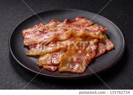 Fried smoked bacon slices, ham, jamon, or prosciutto strips for cooking. Fried bacon Fried smoked bacon slices, ham, jamon, or prosciutto strips for cooking. Fried bacon 135762734
