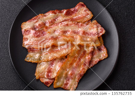 Fried smoked bacon slices, ham, jamon, or prosciutto strips for cooking. Fried bacon Fried smoked bacon slices, ham, jamon, or prosciutto strips for cooking. Fried bacon 135762735