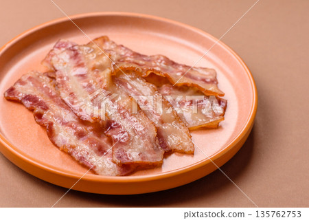 Fried smoked bacon slices, ham, jamon, or prosciutto strips for cooking. Fried bacon Fried smoked bacon slices, ham, jamon, or prosciutto strips for cooking. Fried bacon 135762753
