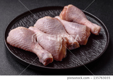 Chicken meat, raw drumsticks on the bone for grilling with salt and spices. Raw chicken drumsticks Chicken meat, raw drumsticks on the bone for grilling with salt and spices. Raw chicken drumsticks 135763035
