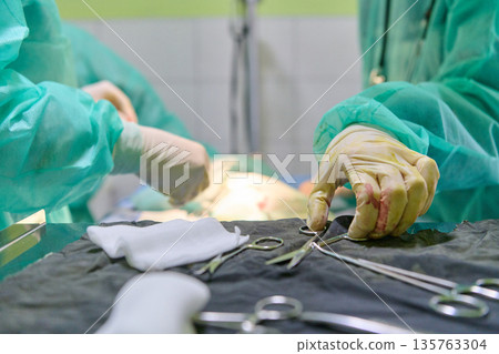 Surgeons At Work During Operation With Medical Tools In An Operating Room Surgeons At Work During Operation With Medical Tools In An Operating Room 135763304