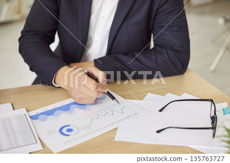 Businessman Working With Financial Documents, Graphs, And Charts In The Office 135763727