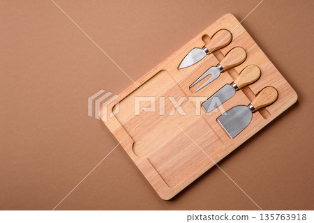 A set of cheese knives with a wooden cutting board, slicing tools. Cheese knives A set of cheese knives with a wooden cutting board, slicing tools. Cheese knives 135763918