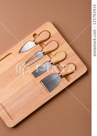 A set of cheese knives with a wooden cutting board, slicing tools. Cheese knives 135763919