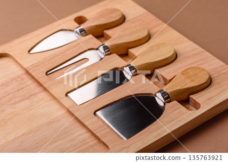 A set of cheese knives with a wooden cutting board, slicing tools. Cheese knives 135763921