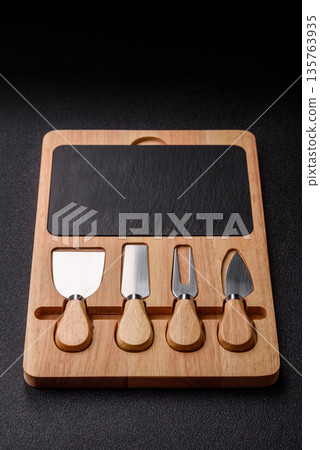 A set of cheese knives with a wooden cutting board, slicing tools. Cheese knives A set of cheese knives with a wooden cutting board, slicing tools. Cheese knives 135763935