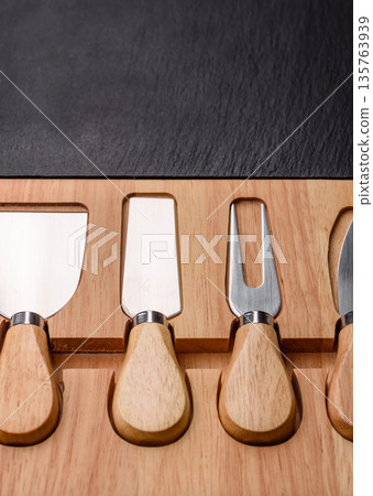 A set of cheese knives with a wooden cutting board, slicing tools. Cheese knives 135763939