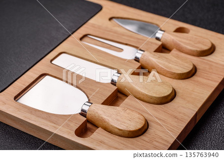 A set of cheese knives with a wooden cutting board, slicing tools. Cheese knives 135763940