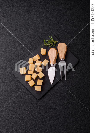 Cubed cheddar, gouda, or parmesan cheese on a cutting board. Cubed cheese 135764090