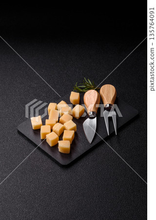 Cubed cheddar, gouda, or parmesan cheese on a cutting board. Cubed cheese 135764091