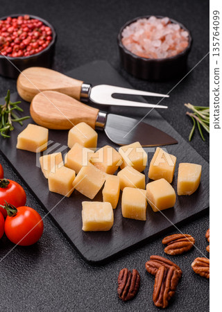 Cubed cheddar, gouda, or parmesan cheese on a cutting board. Cubed cheese 135764099