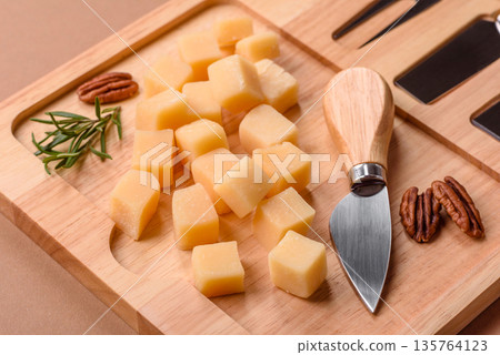 Cubed cheddar, gouda, or parmesan cheese on a cutting board. Cubed cheese 135764123